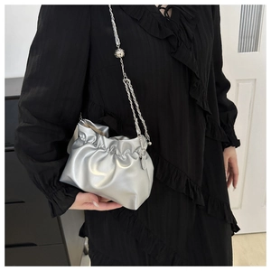 Close-up of metallic silver pleated cloud bag with elegant metal chain shoulder strap