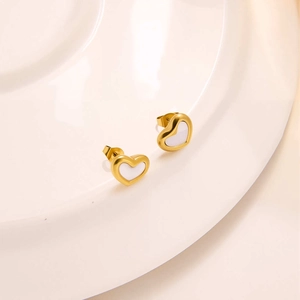 Detailed close-up of heart-shaped gold studs with white enamel on a white ceramic plate
