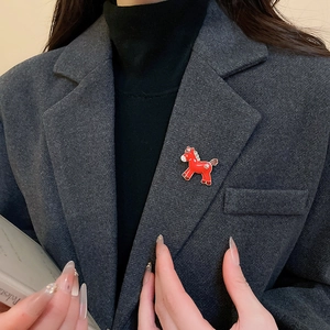 Detail of red enamel horse brooch with gold trim and starry accents on dark grey blazer