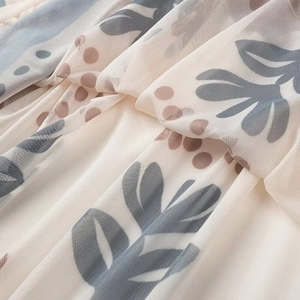 Macro shot of breathable beige mesh fabric featuring gray leaf and pink dot prints
