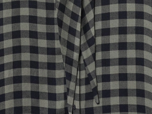 Detailed macro view of dark grey and green plaid fabric with black buttons on a shirt