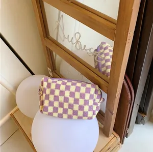 Detailed close-up of knitted checkerboard makeup bag in purple and yellow with zipper
