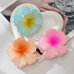 Detailed view of three colorful floral hair claws in gradient blue, orange, and pink colors