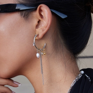 Detail of two-tone 18K gold and silver C-shape earring with pearl and tassel on model
