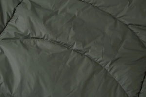 Detailed macro view of dark green quilted fabric stitching on warm hooded long coat