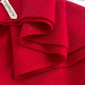 Vista macro del tessuto rosso effetto cashmere con etichetta del marchio cucita