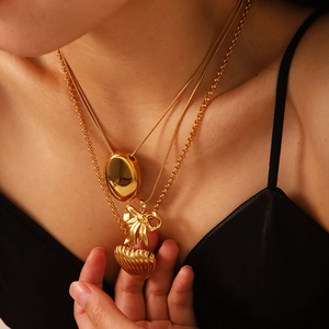 Macro view of triple-layered gold stainless steel necklace with butterfly and heart charms