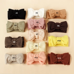Detailed flat lay of thirteen knit ribbed baby headbands with bows in assorted colors