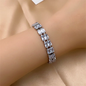 Close-up of sparkling rectangle-cut zircon bracelet on wrist with elegant silk backdrop