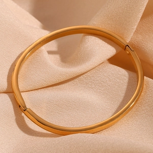 Detailed macro of a 18K gold-plated oval bracelet on a beige silk background