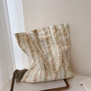Detail of floral canvas tote bag showing orange-brown flower stripes and decorative label