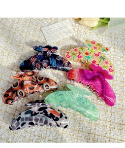 Flat lay of floral and leopard print acetate hair claws on a textured beige background