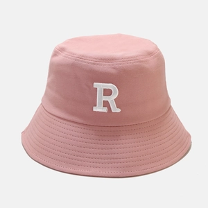 Détail du bob en toile rose avec broderie blanche lettre R et bordure surpiquée