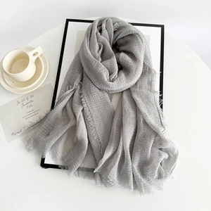 Detail shot of light gray pleated cotton linen scarf with natural frayed edges texture