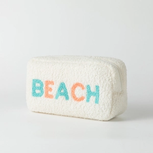 Détail d'une trousse à maquillage pelucheuse avec broderie BEACH en relief coloré