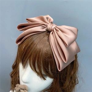 Champagne satin triple-layered large bow headband displayed on a mannequin head model