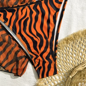 Detailed macro shot of tiger print bikini fabric and breathable mesh cover-up set