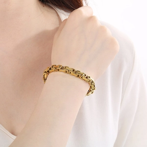Close-up of a gold Byzantine square link chain bracelet worn on a woman's wrist