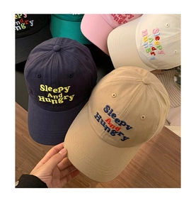 Stack of colorful cotton baseball caps featuring sleepy and hungry embroidery detail