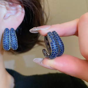 Close-up of deep blue zircon crystals inlaid on U-shaped double-layer hoop earrings