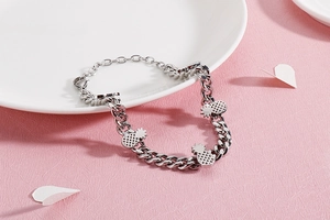 Detail of silver pineapple charms on a thick metal link chain bracelet with lobster clasp