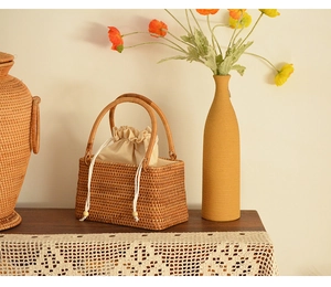 Detail of a handmade woven rattan picnic basket with a cream drawstring inner liner bag
