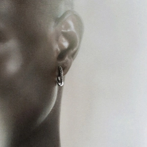 Close-up of minimalist two-tone silver and gold hoop earring with white diamond on ear