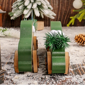 Détail de petites voitures en bois vert foncé avec décor de sapin enneigé pour Noël