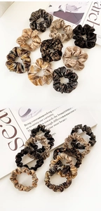 Detailed close-up of glossy scrunchies in brown, champagne and leopard print patterns