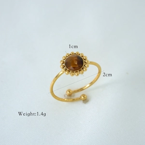 Detail of adjustable gold ring featuring a brown natural stone with beaded edge detail
