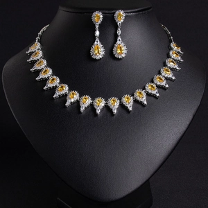 Detailed view of silver necklace and earrings set with yellow pear-shaped gemstones