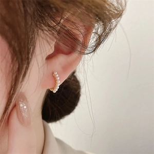 Close-up of minimalist gold pearl hoop earrings worn by a model for a chic look