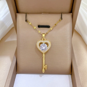 Close-up of gold heart key pendant with sparkling pavé crystals on silk background