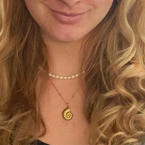 Detail view of 18k gold plated conch pendant and pearl necklace layered on neck