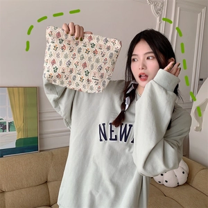 Detailed close-up of a beige floral cotton makeup bag held by a model in a natural setting