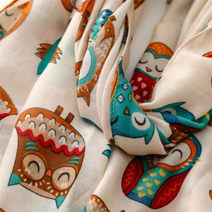 Detailed macro view of beige scarf featuring colorful cartoon owl pattern and soft texture