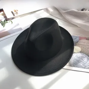 Close-up of black wide-brim wool fedora hat with classic indented crown and soft lighting