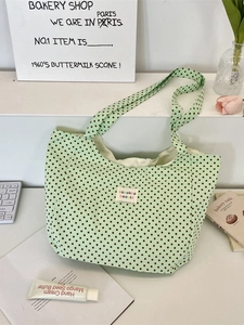 Mint green polka dot canvas tote bag with wide straps shown in a lifestyle desk setting