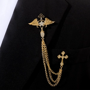 Broche de col dorée avec croix ailée, chaînes et cristaux sur un revers de costume