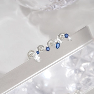 Macro shot of silver stud earrings set with blue geometric gems and white zircons