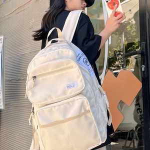 Minimalist off-white multi-pocket nylon backpack for students shown in a lifestyle setting
