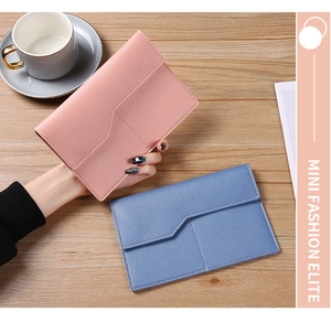 Lifestyle shot of pink and blue PU leather passport card holders on a wooden table