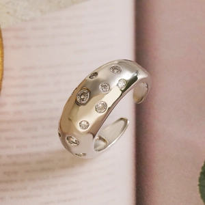 Minimalist silver open ring with scattered zircon stones on a soft pink background
