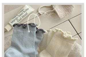 Close-up of ribbed cotton crew socks with delicate ruffle trim in blue and off-white