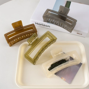 Close-up of four large rectangular hair claws in translucent resin on a beige tray