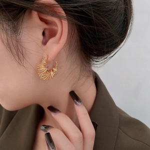 Macro detail of gold plated spiral earrings showing intricate twisted metal wire texture