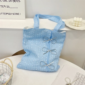 Macro detail of light blue sequined tote bag with three metallic silver bows on front