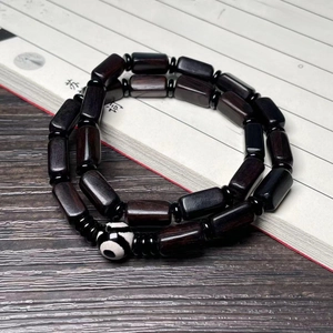 Close-up of black ebony barrel bead bracelet with Dzi bead on calligraphy scroll