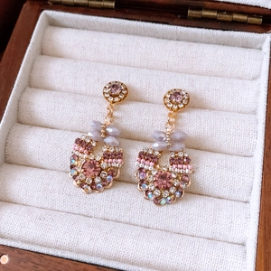 Detail view of vintage style gold-toned earrings with faceted crystals in a jewelry box