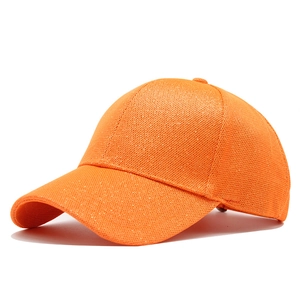 Detail view of bright orange baseball cap with shimmering sequins and mesh texture
